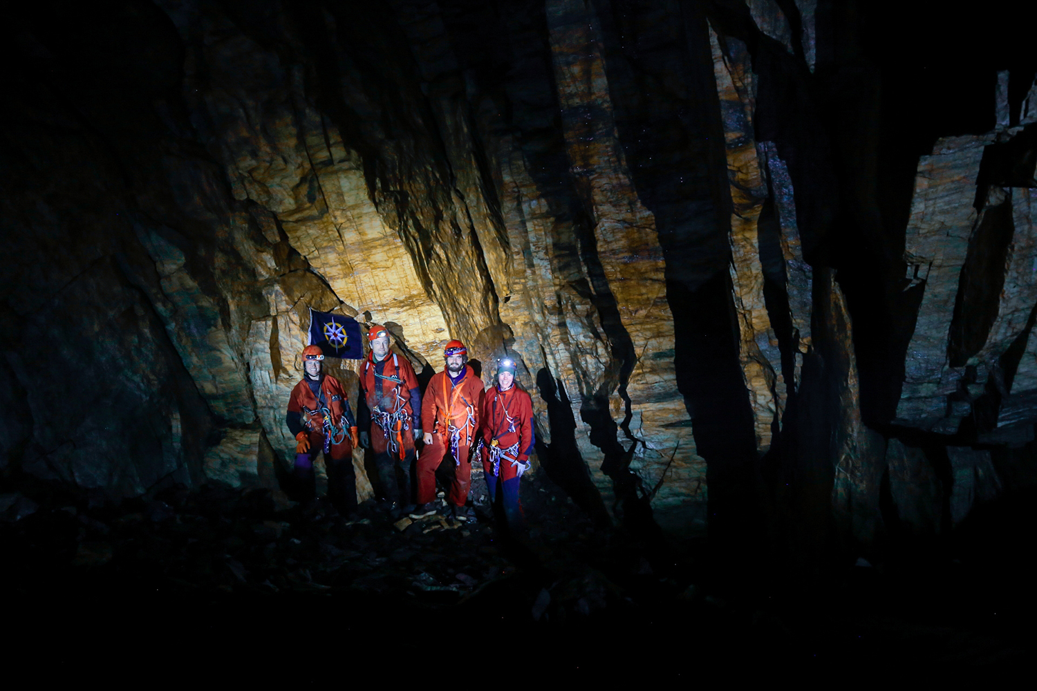 the Jawdrop team inside the cave with the flag of the Royal Canadian Geographical Society
