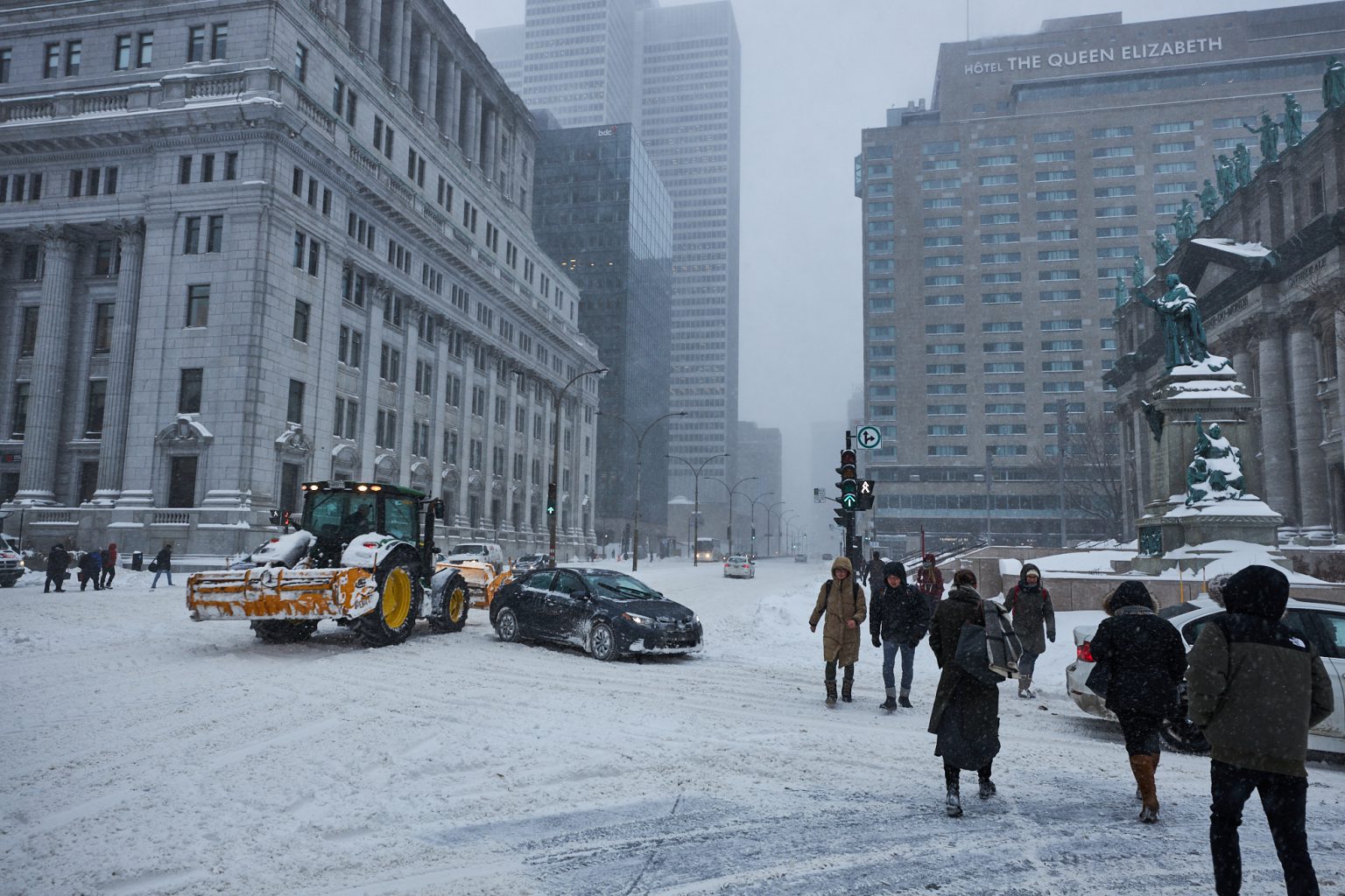 Pedestrians and cars cross a snowy intersection in downtown Montreal