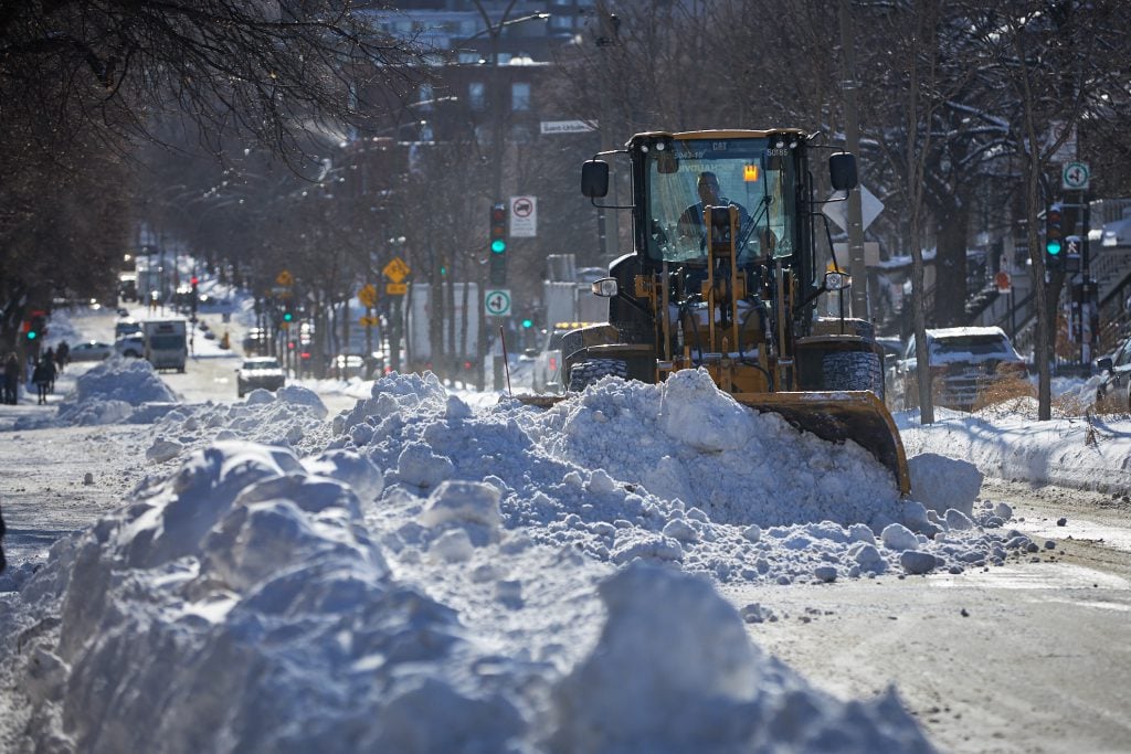 A snowplow pushes snow down the street.