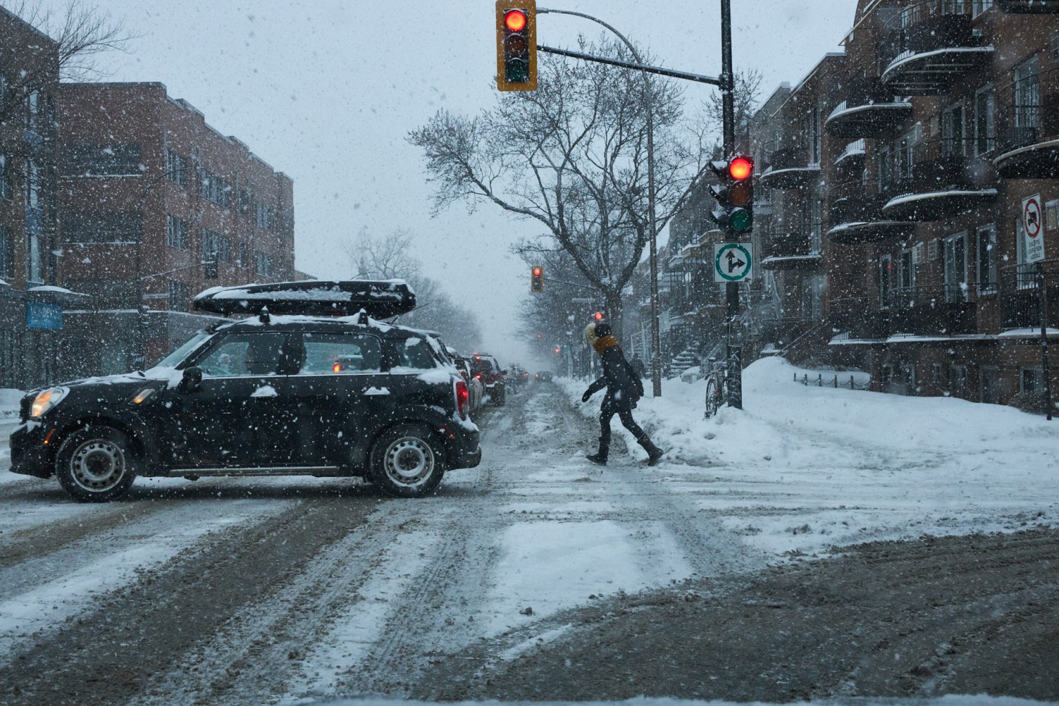 Cars and pedestrians cross a snowy intersection in Montreal