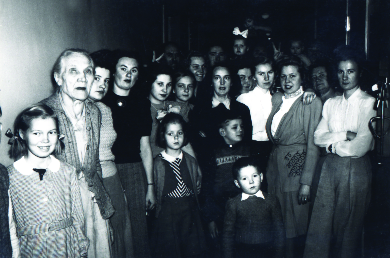 A black and white photo of women sitting and standing looking at the camera