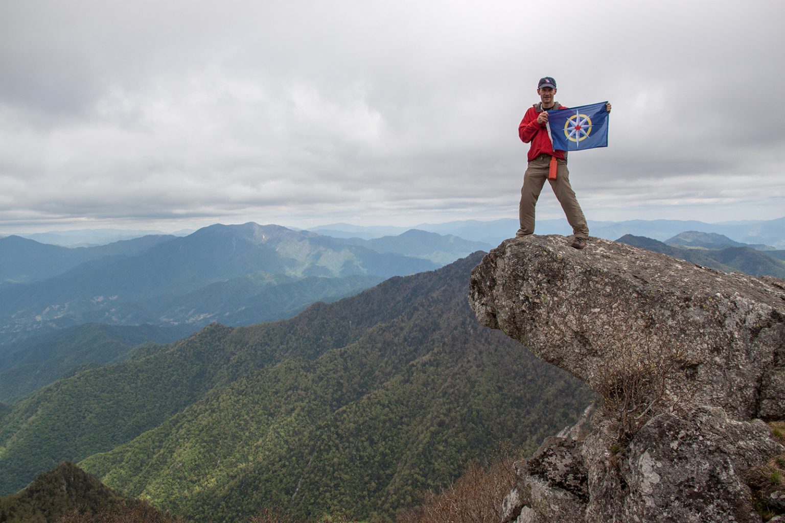 George Kourounis displays the flag of the RCGS atop Piro Peak, the tallest point in the Myohyang Mountains of central North Korea. (Photo courtesy George Kourounis) 