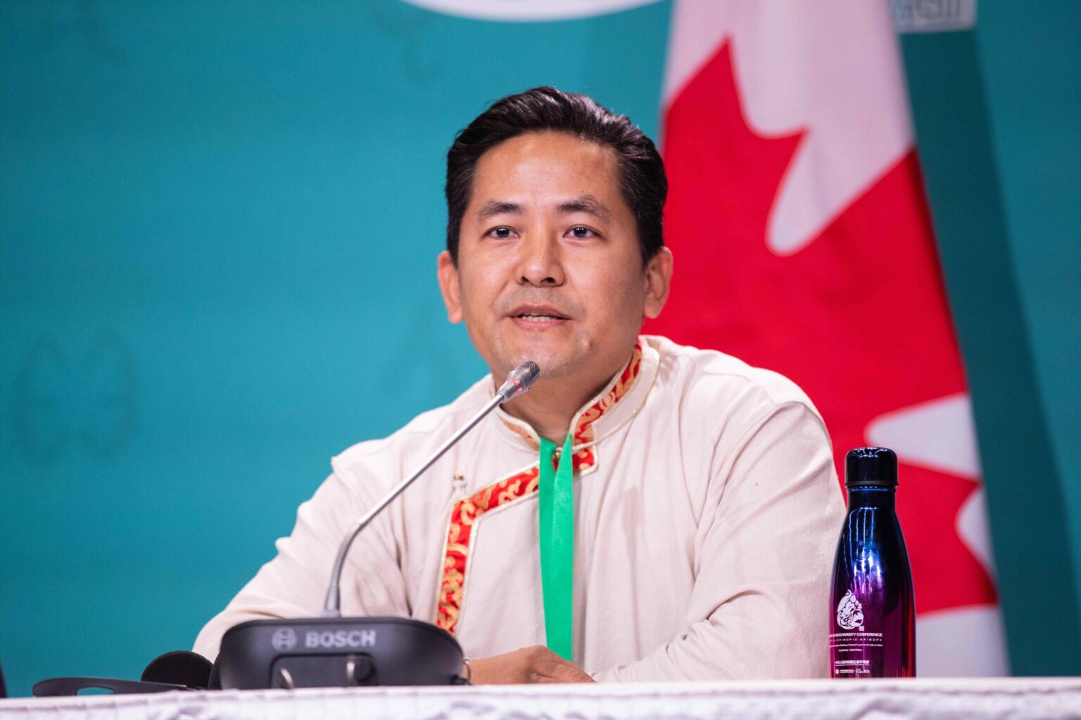 Lakpa Sherpa sits on a panel, with the Canadian flag behind him.