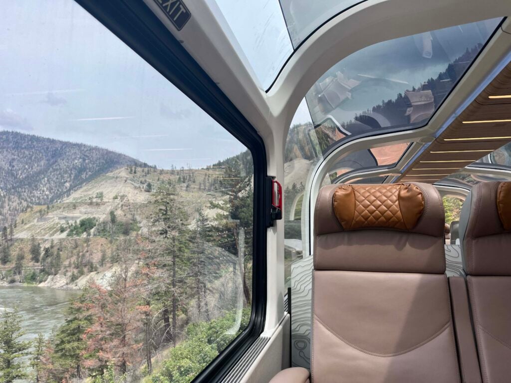 A view of some dry mountains from a glass-domed rail car