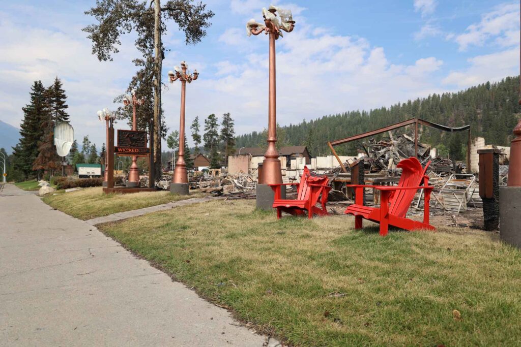 fire damage has warped streetlamps and red plastic muskoka chairs. Behind them are burned out buildings