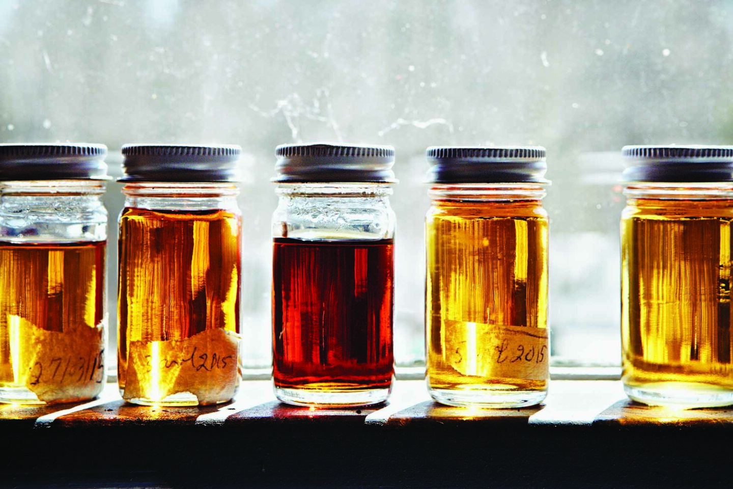 Jars filled with different colours of maple syrup.
