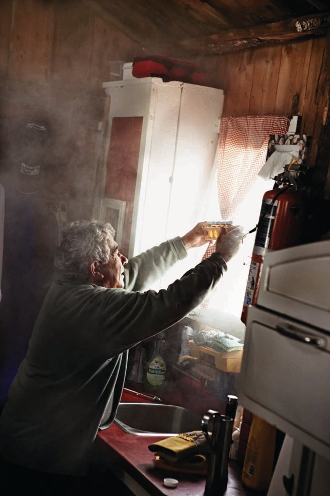 a man holds a jar of syrup up to a window to check its colour