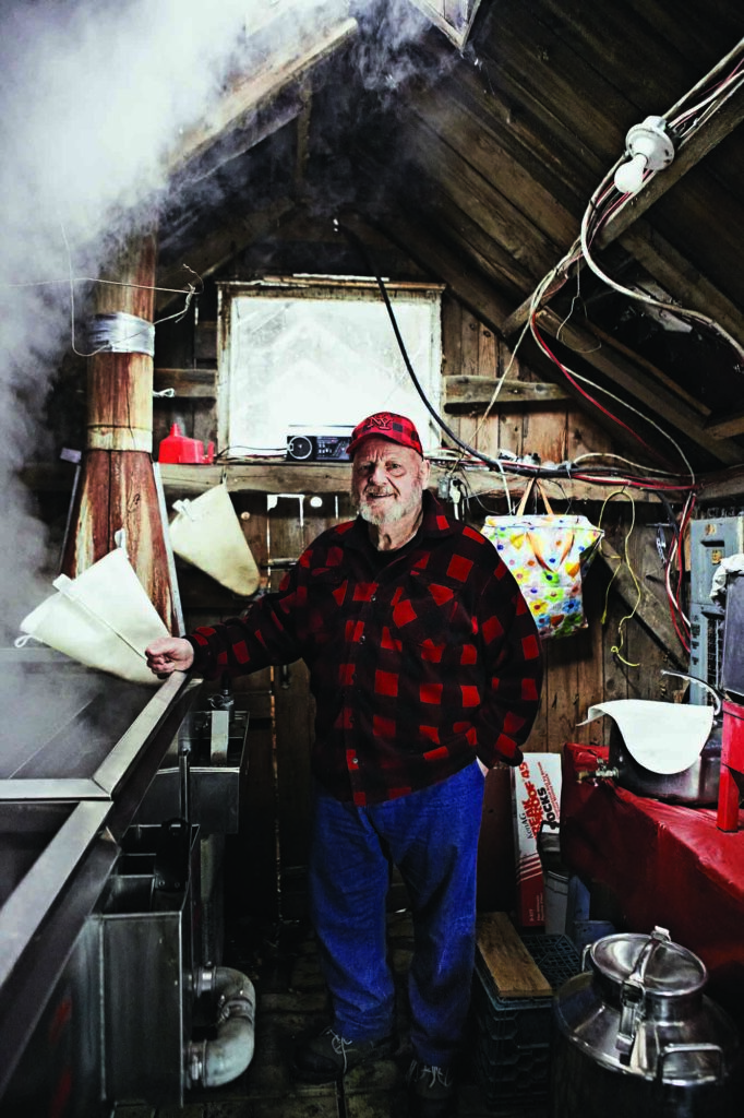 A man stands in a room where maple sap is being boiled into syrup