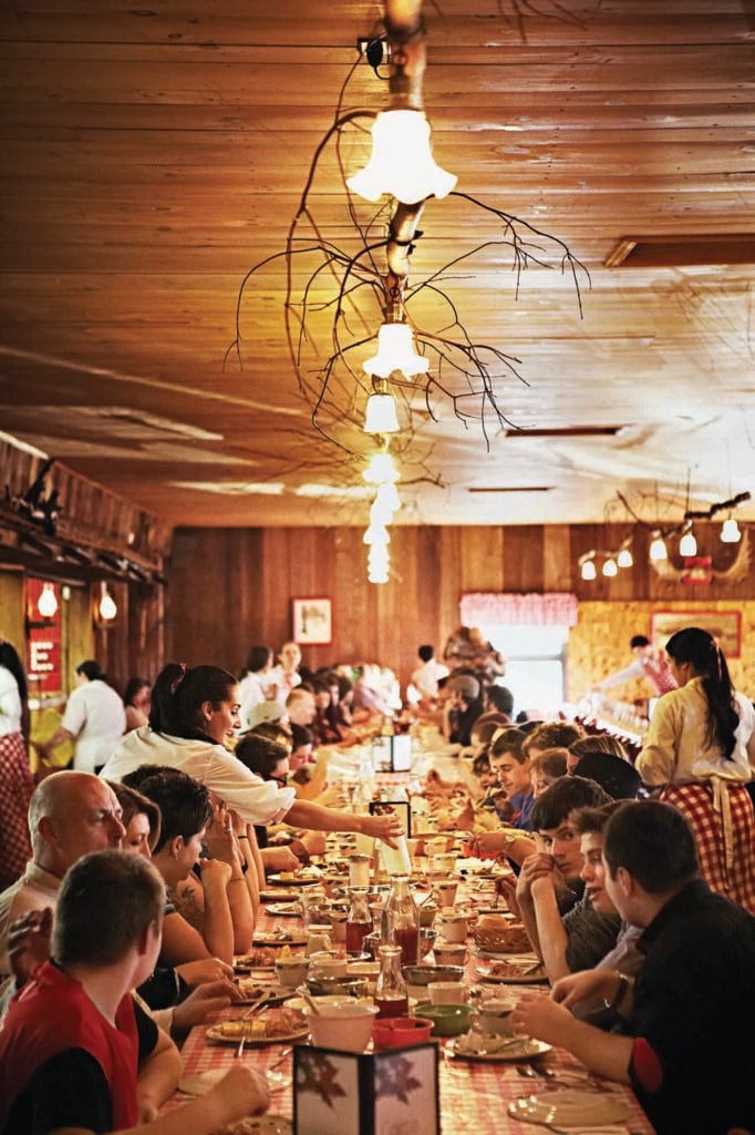 Guests sit at a long table to enjoy food and drink at a sugar shack