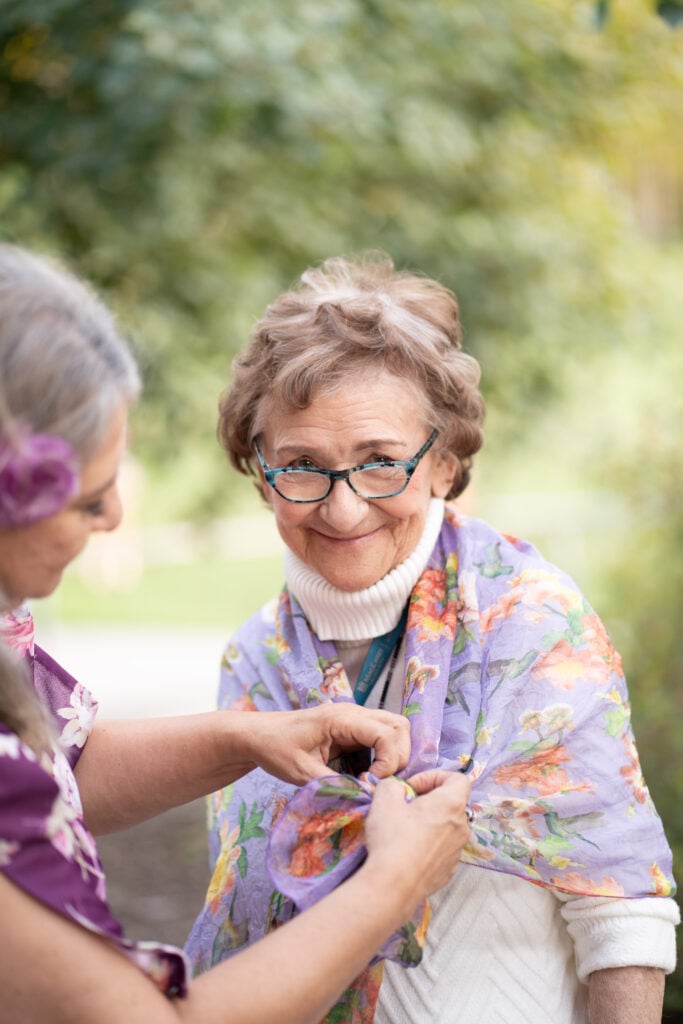 A woman pins Maggie Hodgson's scarf over her shoulders