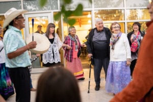 Maggie Hodgson stands in the middle of a circle of people dancing at her 80th birthday party