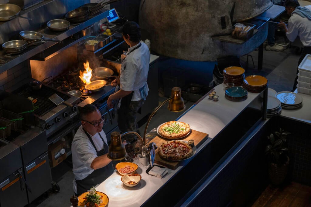 A chef cooks pizza in a kitchen